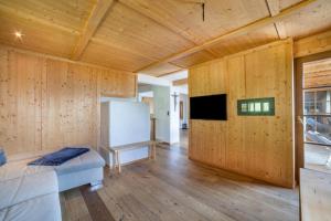 een kamer met houten wanden, een bed en een televisie bij Fewo Bergpanorama Obertalerhof in San Martino