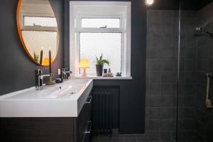 a bathroom with a sink and a mirror and a shower at Luxury Apartment In Prime Location Ocean View in Reykjavík
