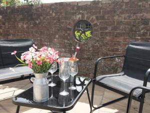 a table with wine glasses and flowers on a patio at Redlands Cottage Surrey Hills in Dorking