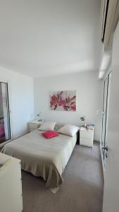 a white bedroom with a bed with a red pillow at Les Pieds dans l'Ô - Appartement 50m2 Front de mer in Saint-Cyr-sur-Mer