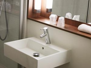 un lavabo blanc dans une salle de bain avec un miroir dans l'établissement Campanile Clermont Ferrand - Le Brezet, à Clermont-Ferrand 29 autres photos