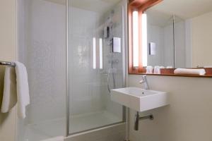 une salle de bain avec une douche en verre et un lavabo dans l'établissement Campanile Clermont Ferrand - Le Brezet, à Clermont-Ferrand