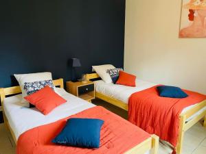 a room with two beds with orange and blue pillows at Jolie maison LE TEICH bassin Park/wifi in Le Teich