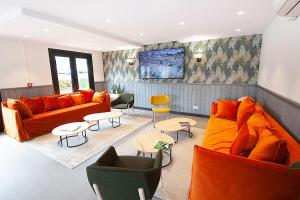 - un salon avec deux canapés et tables orange dans l'établissement Campanile Clermont Ferrand - Le Brezet, à Clermont-Ferrand