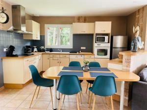 a kitchen with a wooden table and blue chairs at Jolie maison LE TEICH bassin Park/wifi in Le Teich