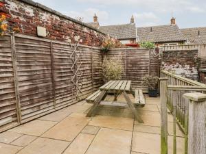 a wooden bench sitting on a patio next to a fence at Butter Cross in Scarborough
