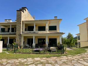 uma casa grande com uma cerca em frente em Faraway Lake em Ferreira do Zêzere