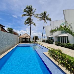 una piscina junto a un edificio con palmeras en Maria Farinha Residence Prince - LocarHouse en Paulista