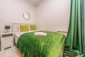 a bedroom with a bed with a green blanket at Apartament Starogdański 21 in Gdańsk