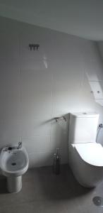 a white bathroom with a toilet and a sink at APARTAMeNTOS DON MANUEL A in Cee
