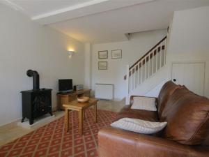 a living room with a leather couch and a stove at Noel Cottage in Chipping Campden