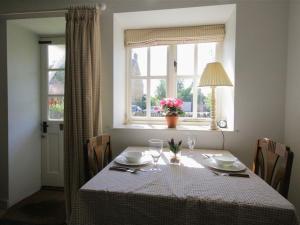 a dining room table with a white table cloth and a window at Noel Cottage in Chipping Campden