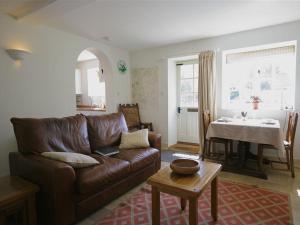 a living room with a brown leather couch and a table at Noel Cottage in Chipping Campden