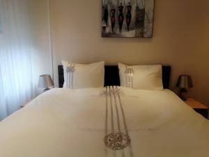 ein weißes Bett mit weißer Bettwäsche und Kissen in der Unterkunft Border Bliss - Private Room with Bathroom in a Cozy Home in Kerkrade