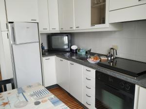 ラヴァーニャにあるCasa al mareの白いキャビネットと黒の電化製品が備わるキッチン