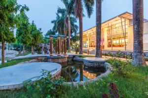 a building with palm trees and a pond in front of it at Royal Tiger Luxury Resort in Sauraha