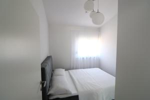 biała sypialnia z łóżkiem i oknem w obiekcie Vrsi Apartments w mieście Vrsi