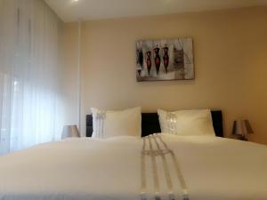 ein Schlafzimmer mit einem großen weißen Bett mit weißen Kissen in der Unterkunft Border Bliss - Private Room with Bathroom in a Cozy Home in Kerkrade