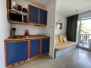 eine Küche mit blauen Schränken, einem Waschbecken und einem Sofa in der Unterkunft Appartement Urrugne, 2 pièces, 4 personnes - FR-1-239-755 in Urrugne