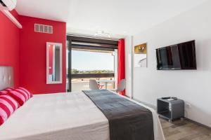 een slaapkamer met rode muren en een bed met een televisie bij Studio Vue mer panoramique, piscine Port Vénus village naturiste in Cap d'Agde