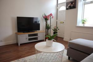 ein Wohnzimmer mit einem TV und einem Tisch mit Blumen in der Unterkunft Modern 3-bedrooms house with 6 guests in Sheffield