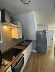 uma cozinha com um frigorífico em aço inoxidável e pisos em madeira em Basingstoke 1x Double bed and Sofa bed em Sherborne Saint John