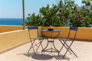 two chairs and a table with a bowl of fruit on it at Spertos Apartments in Órmos