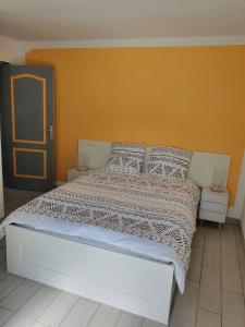 a bedroom with a large bed with an orange wall at Gîte du ronthaunay in Saint-Clément