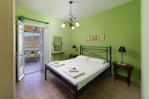 a green bedroom with a bed and a balcony at Spertos Apartments in Órmos