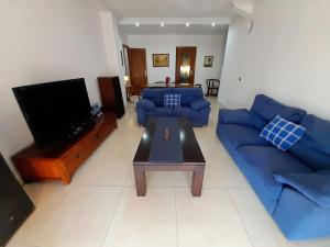 sala de estar con sofás azules y TV en Apartamento Murcia a tus pies, en La Alberca