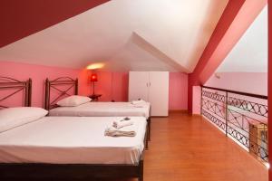 two beds in a room with pink walls and wooden floors at Spertos Apartments in Órmos