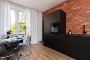 a kitchen with a dining table and a brick wall at Port Gdynia Apartment by Renters in Gdynia