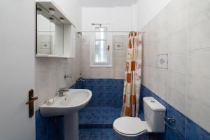 a blue and white bathroom with a toilet and a sink at Spertos Apartments in Órmos