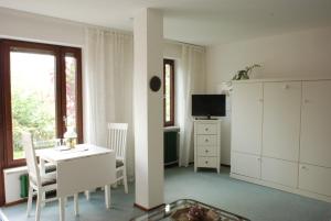 フュッセンにあるHaus Ambiのデスク、テレビ、窓が備わる白い客室です。