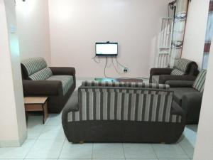 a living room with two couches and a tv at Kaks apartments in Kampala