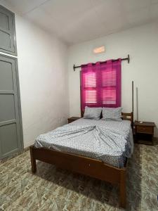 een slaapkamer met een bed en een roze raam bij J Nova LDA in São Tomé +23 foto's