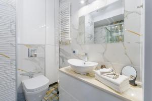 biała łazienka z umywalką i toaletą w obiekcie Apartament Doro w Kołobrzegu