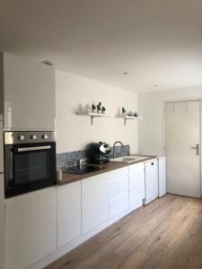 a kitchen with white cabinets and a black stove top oven at Maison Miss Manon in Béthune