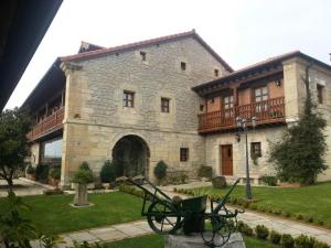 un gran edificio de piedra con una estatua delante de él en Posada La Victoria, en Miengo