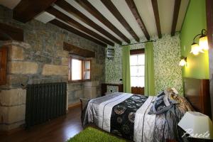 a bedroom with a bed and a stone wall at Posada La Victoria in Miengo