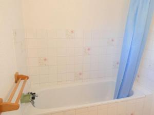 a bathroom with a tub with a blue shower curtain at Appartement Saint-Lary-Soulan, 2 pièces, 6 personnes - FR-1-457-149 in Saint-Lary-Soulan