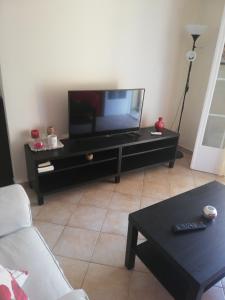 una sala de estar con TV de pantalla plana en un centro de entretenimiento negro en Sunny stay furnished apartment in Kanoni en Kanoni