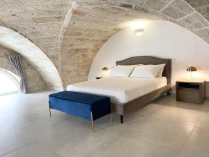 a bedroom with a bed and a stone wall at Casa Le Volte by Ferrocino Holiday in Nardò