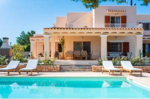 a villa with a swimming pool in front of a house at Can Toni in Sant Josep de sa Talaia