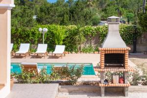 a outdoor fireplace next to a swimming pool with chairs at Can Toni in Sant Josep de sa Talaia