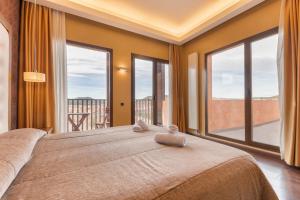 Schlafzimmer mit einem großen Bett und großen Fenstern in der Unterkunft Fuente del Miro in Valderrobres