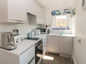 eine weiße Küche mit einer Spüle und einer Mikrowelle in der Unterkunft White Roses Retreat in Betws-y-coed