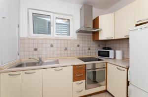 eine Küche mit weißen Schränken, einer Spüle und einer Mikrowelle in der Unterkunft Apartment Nona - Center, 150 meters from the beach in Supetar