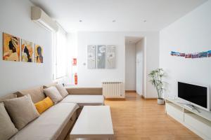 ein weißes Wohnzimmer mit einem Sofa und einem TV in der Unterkunft Cosy Apartment Malasaña in Madrid