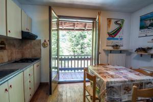 a kitchen with a table and a view of a balcony at 037 - Casa Neve e Natura 200 metri impianti sciistici in Borgata Sestriere